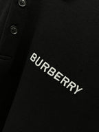 Burberry logo text on black polo shirt with button placket detail.