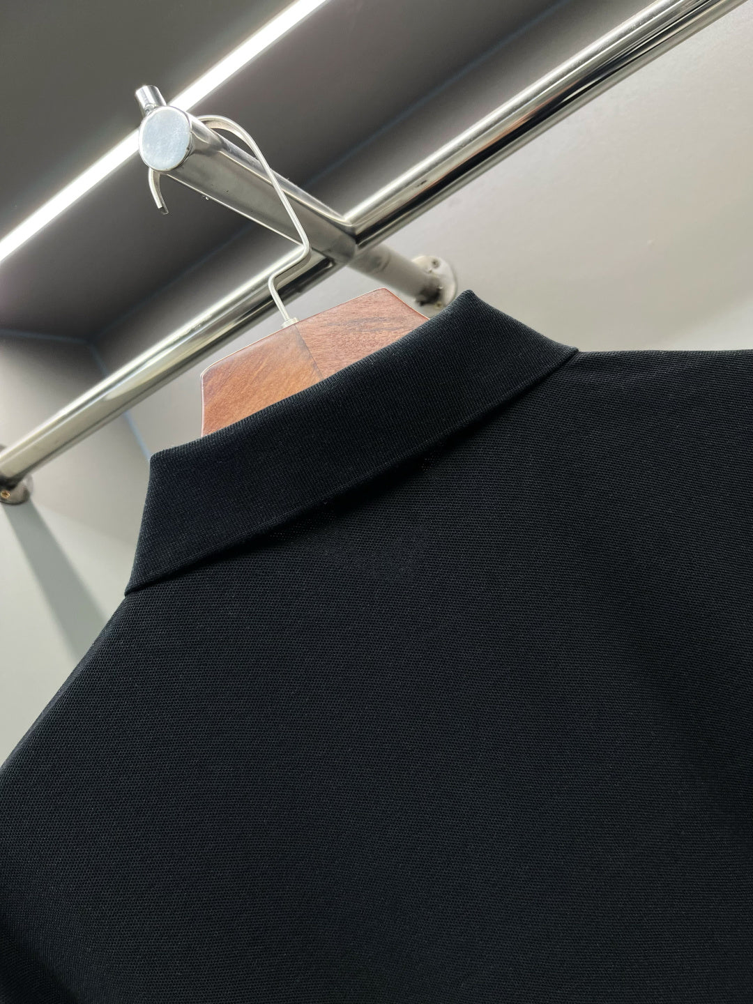 Close-up of black polo shirt shoulder and collar seam at the back.