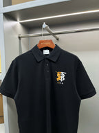 Black short-sleeve polo shirt with pointed collar and embroidered TB 1856 logo.