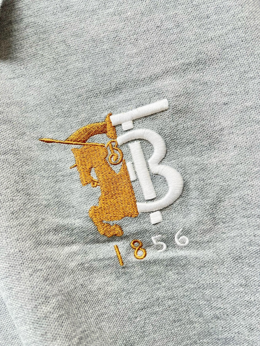 Yellow and white logo embroidery on light gray polo shirt fabric
