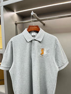 Light gray polo shirt with button placket and yellow horse logo at chest