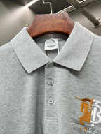 Light gray polo shirt collar with button placket and yellow logo embroidery