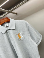 Light gray polo shirt with short sleeves and yellow chest logo