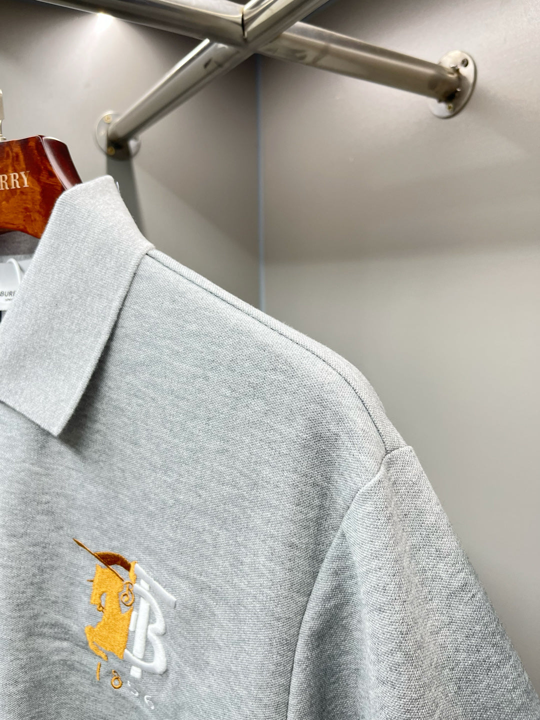 Light gray polo shirt with embroidered yellow logo on side chest