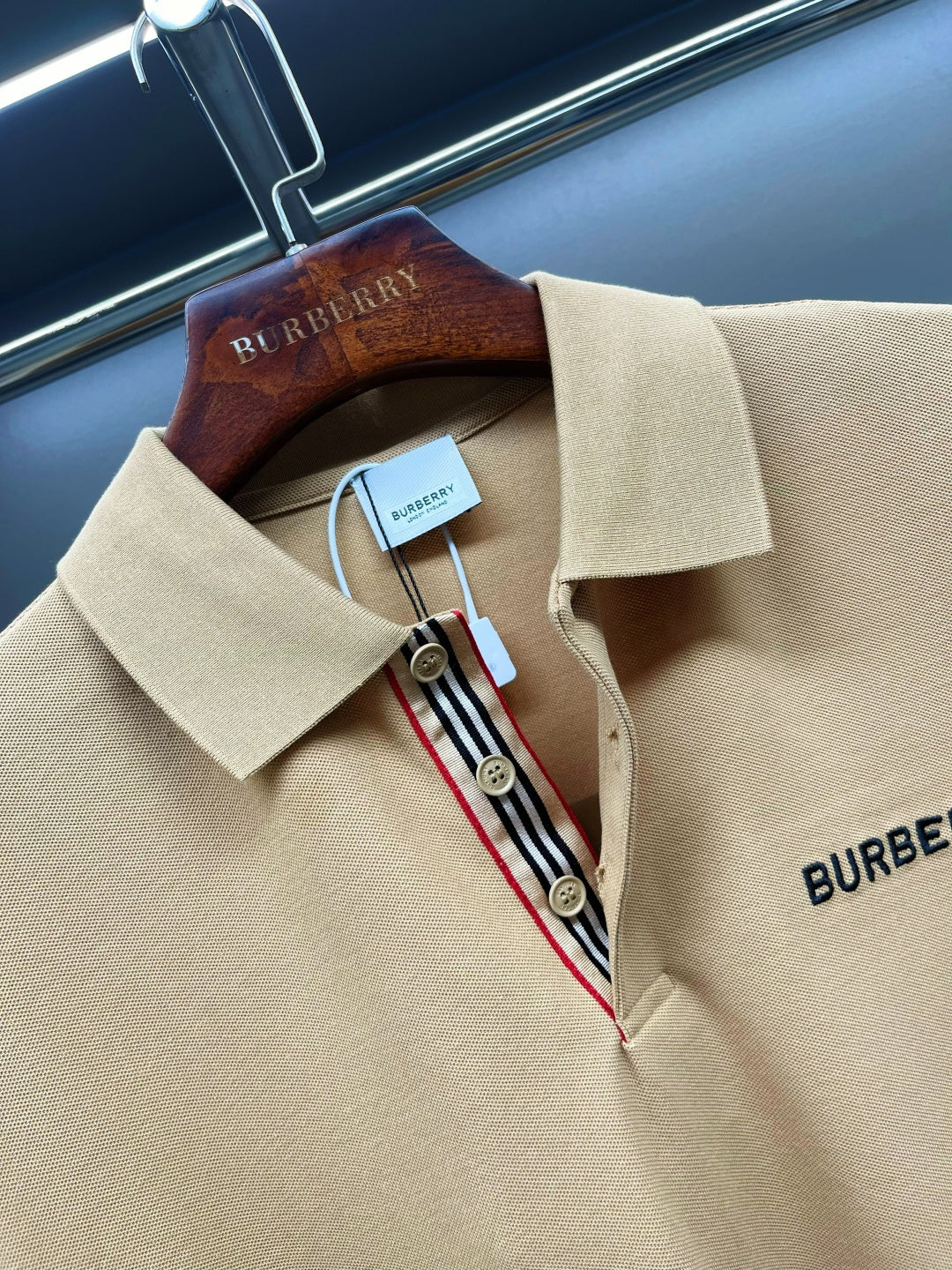 Beige polo shirt neckline detail with Burberry logo patch, button placket, striped trim