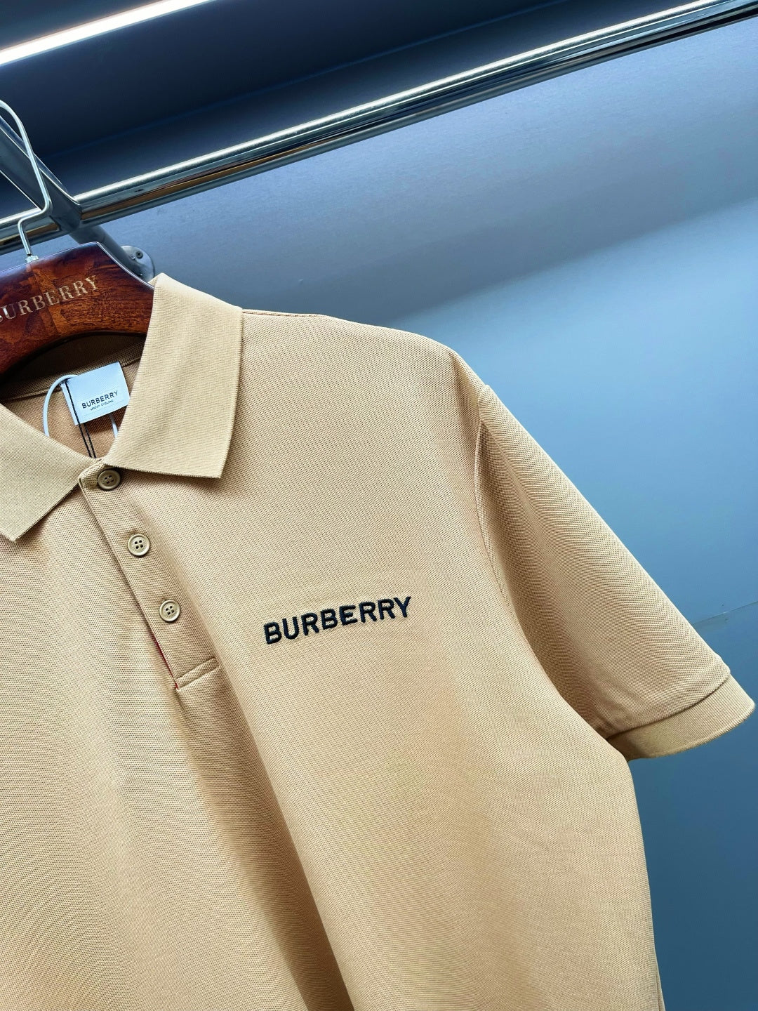 Beige polo shirt close-up of Burberry logo on chest, collared neckline