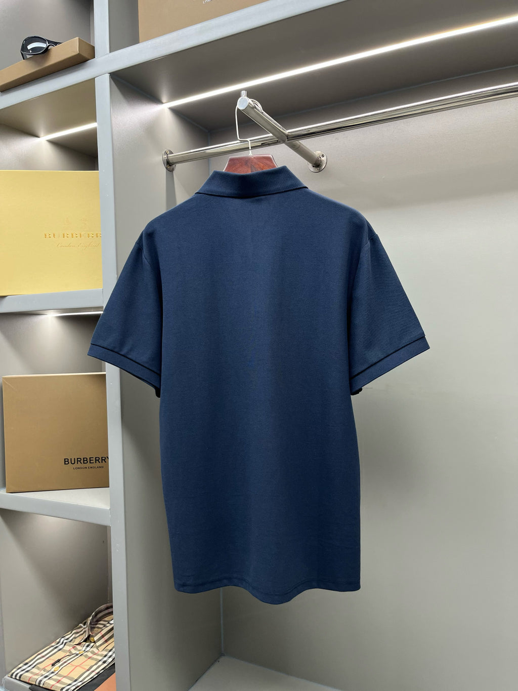Back view of blue Burberry polo shirt on hanger
