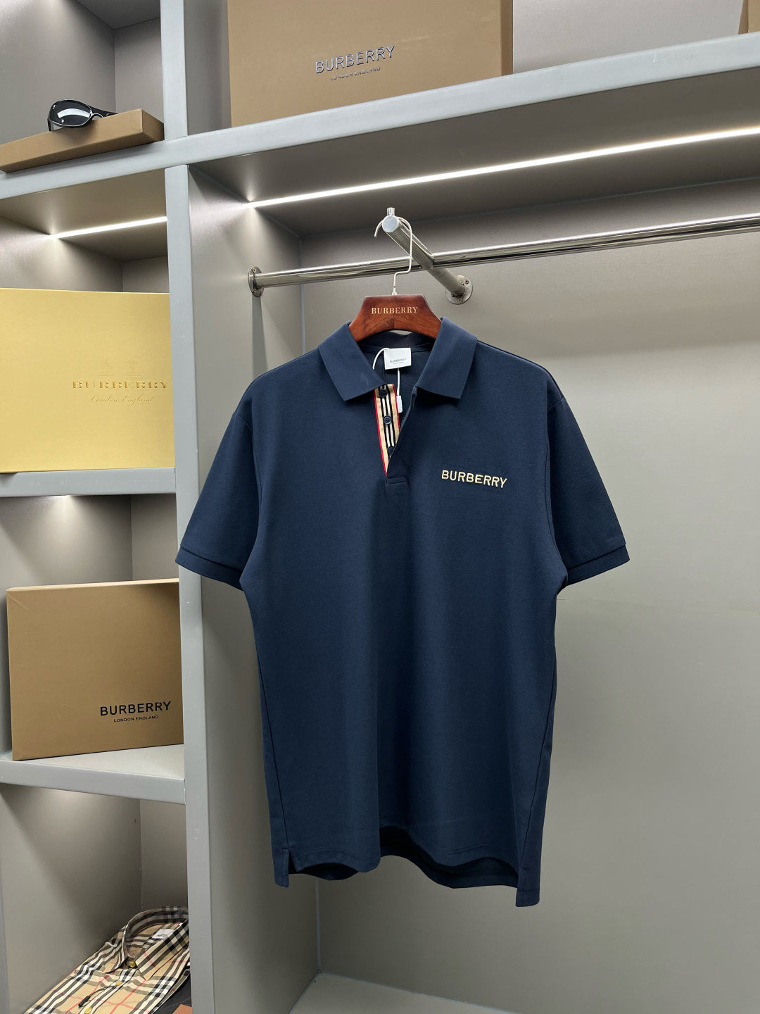 Blue Burberry polo shirt on hanger with buttoned collar and logo