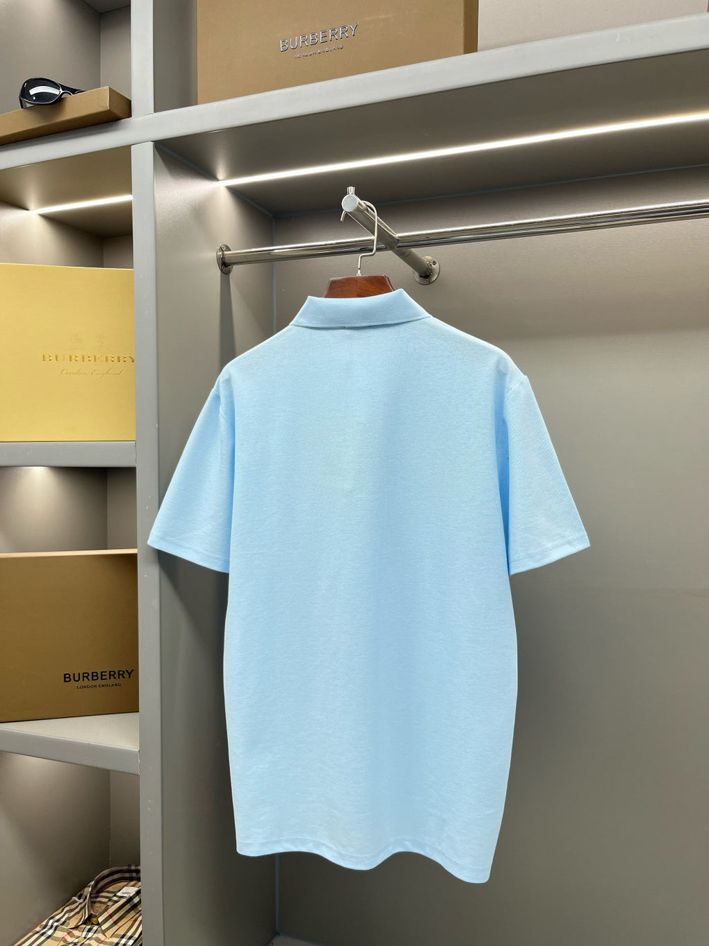 Burberry light blue short-sleeve polo shirt, back view on a hanger
