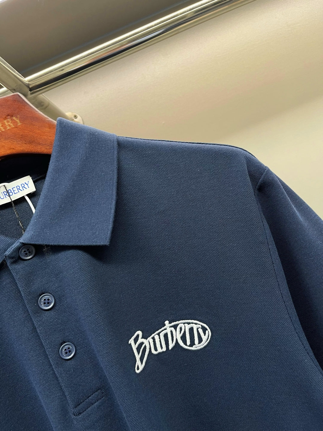 Navy Burberry polo shirt detail: collar, buttons, Burberry logo embroidery