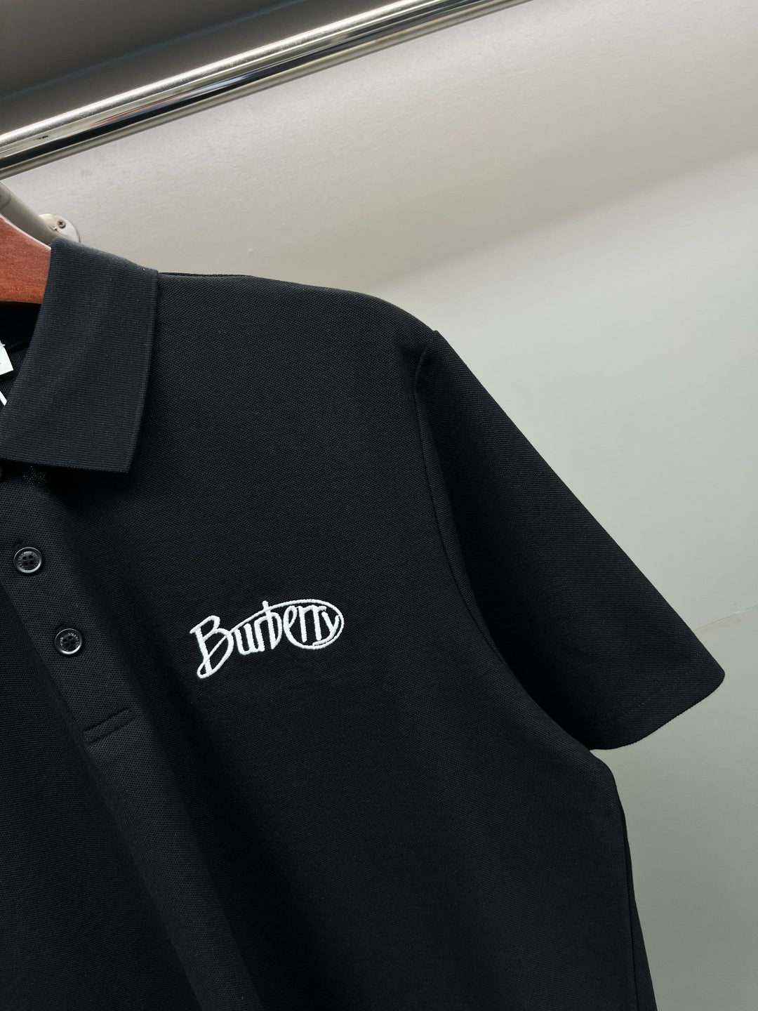 Black polo shirt side view with embroidered Burberry logo on chest