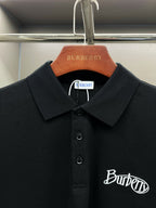 Black polo shirt close-up with pointed collar, button details, and Burberry script logo