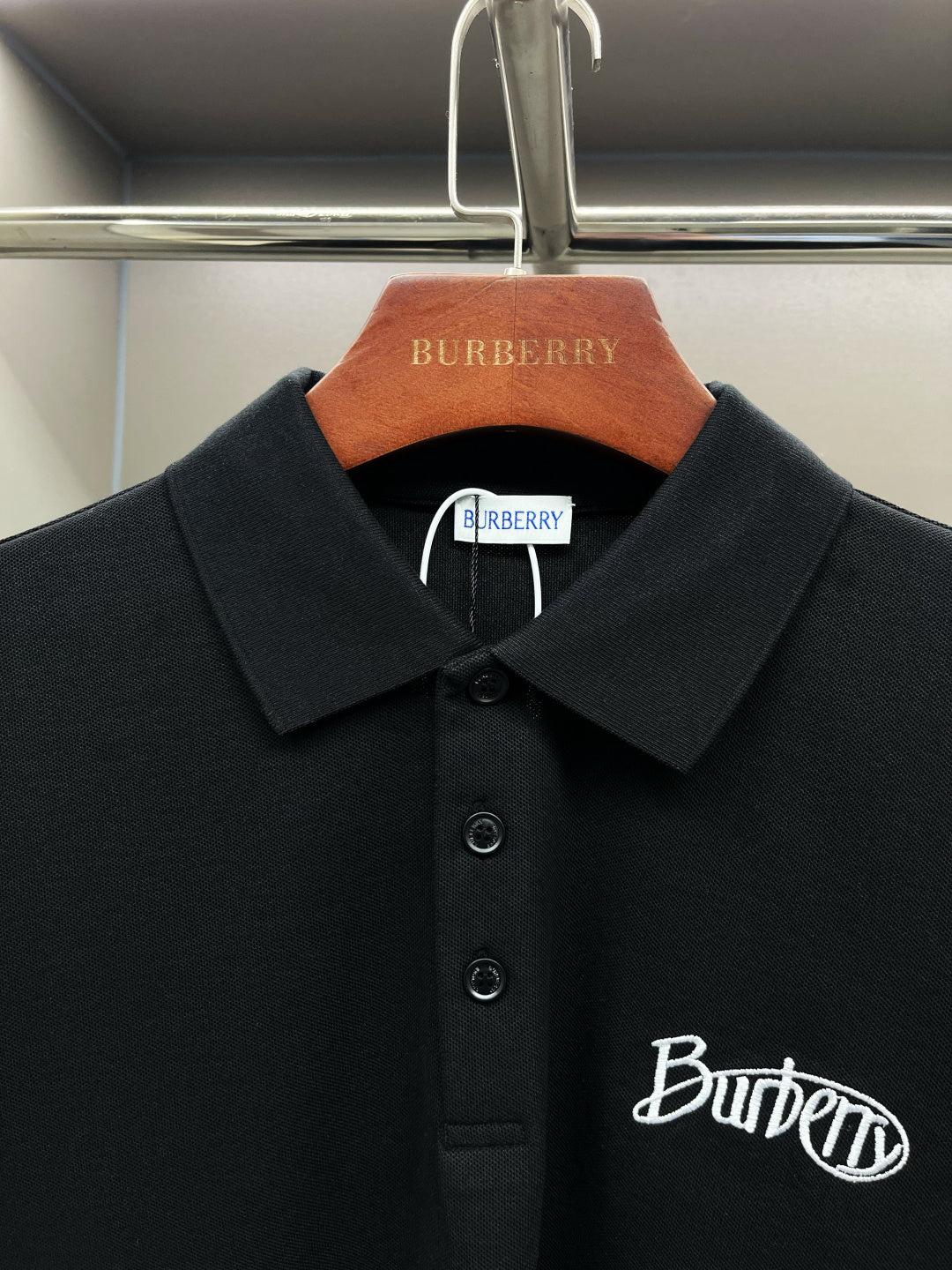Black polo shirt close-up with pointed collar, button details, and Burberry script logo