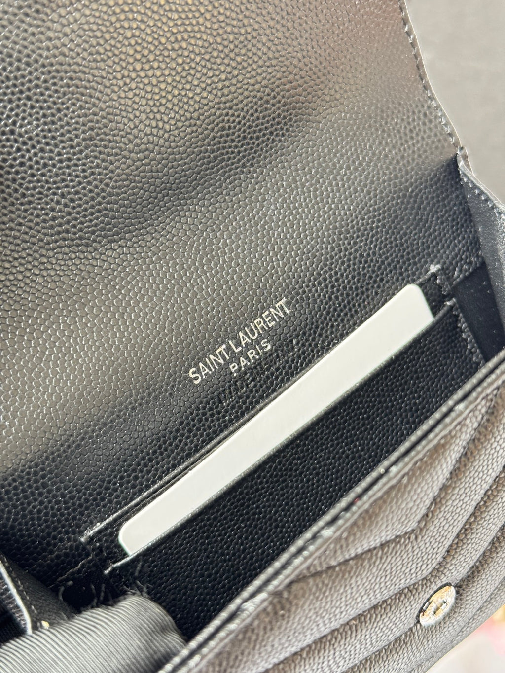 Dark small bag interior close-up with SAINT LAURENT PARIS logo label