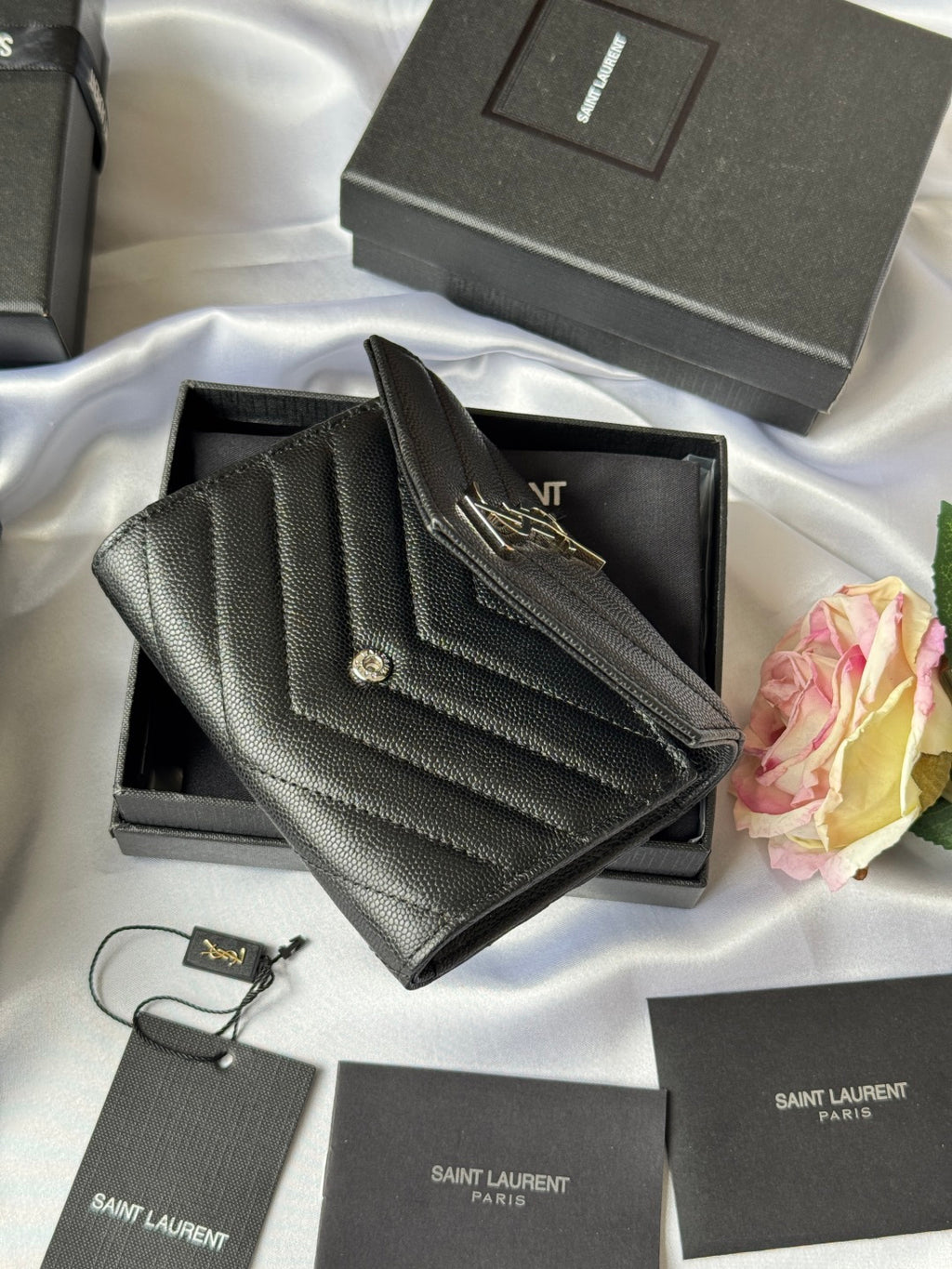 Dark small bag with YSL gold logo flap, resting on open box
