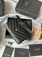 Dark small bag with YSL gold logo flap, resting on open box