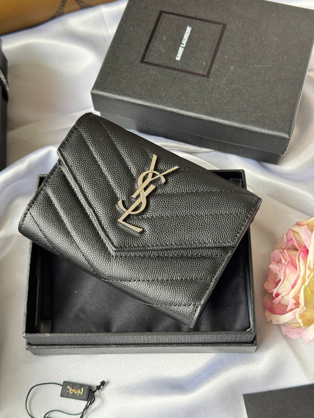 Dark small bag with YSL gold logo and stitched flap detail on display
