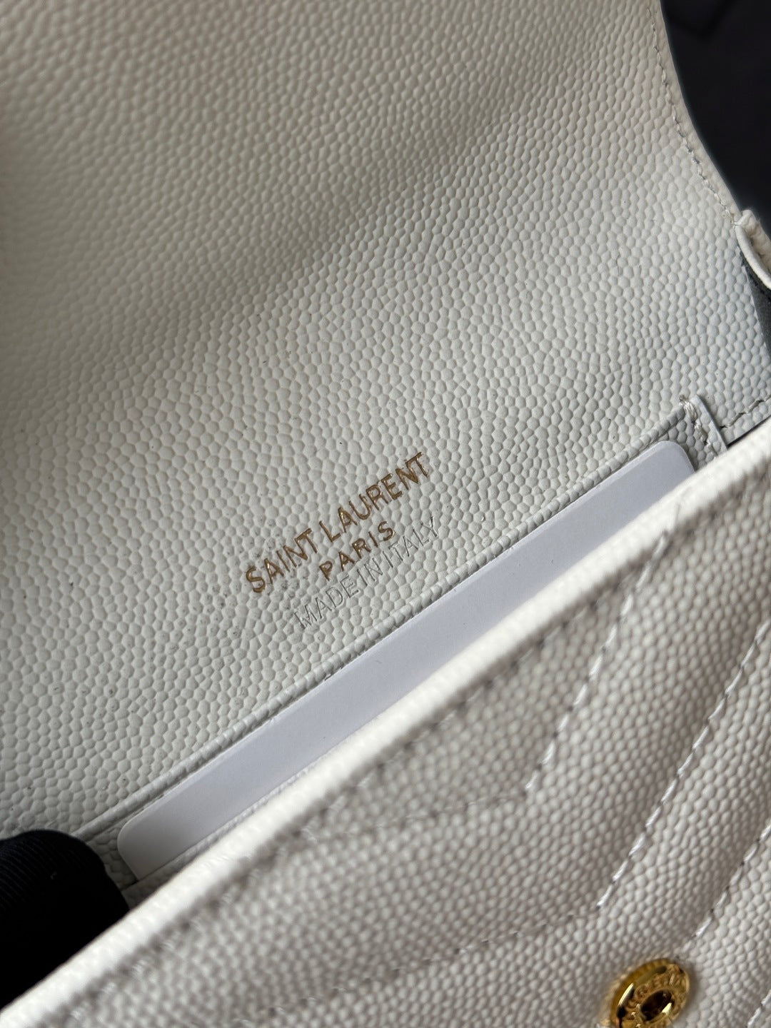 Small bag close-up in light cream with Saint Laurent Paris embossed on strap
