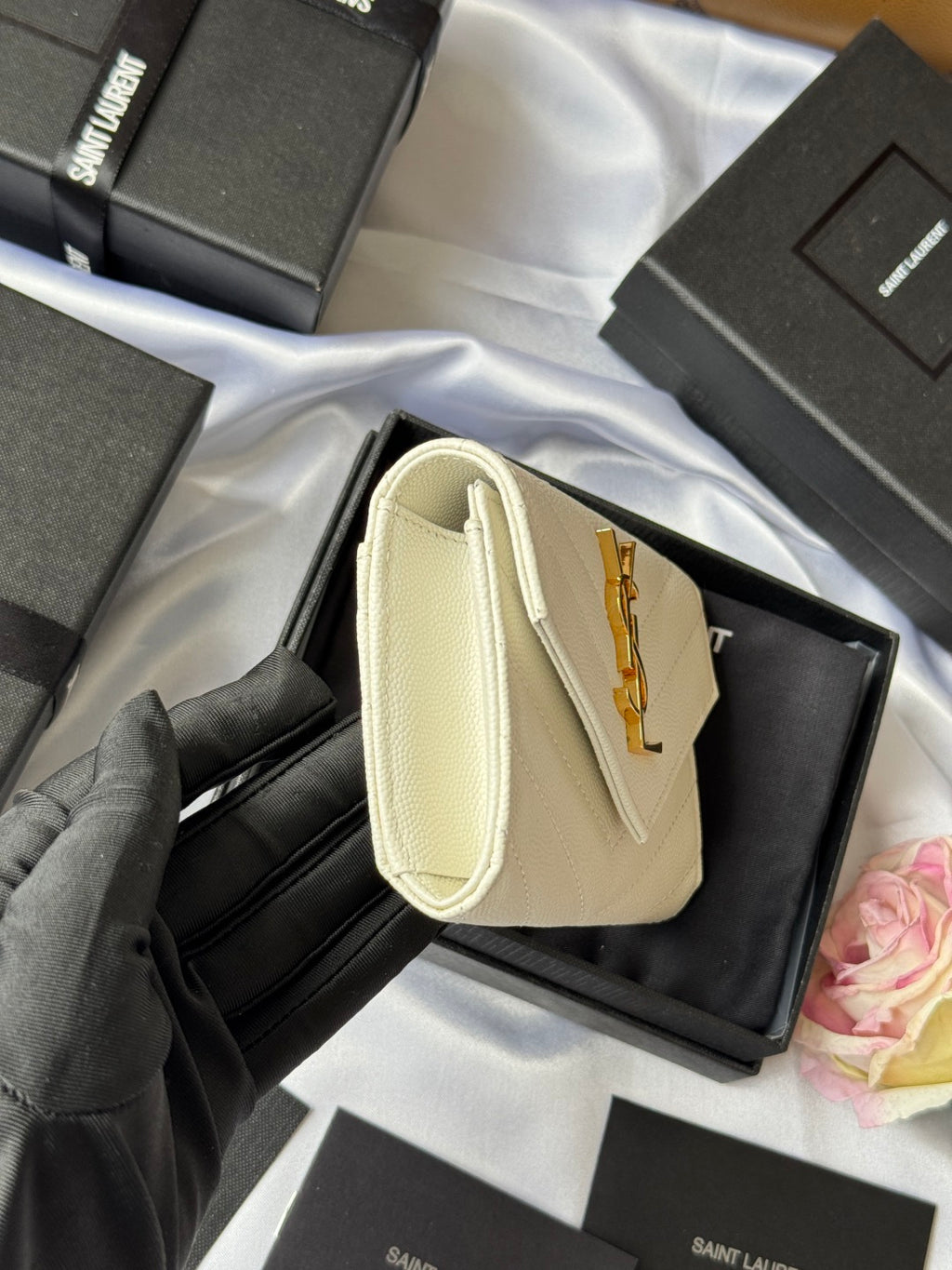 Small bag in light cream with wrist handle, front flap, and gold Saint Laurent logo
