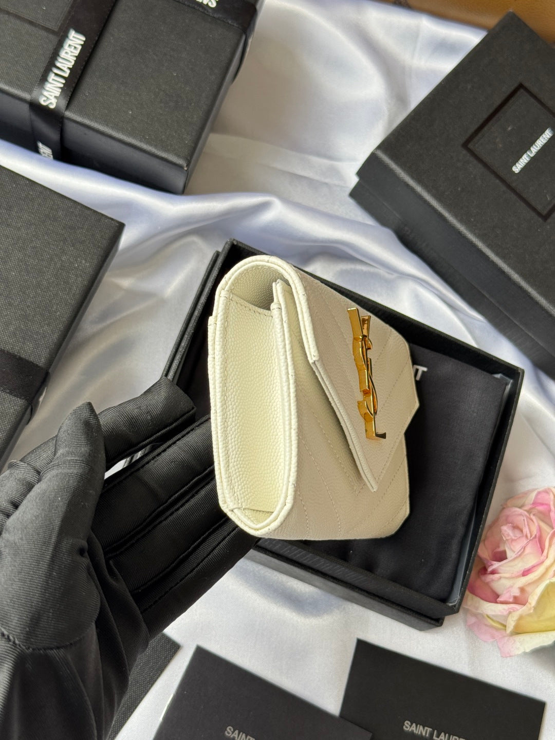 Small bag in light cream with wrist handle, front flap, and gold Saint Laurent logo