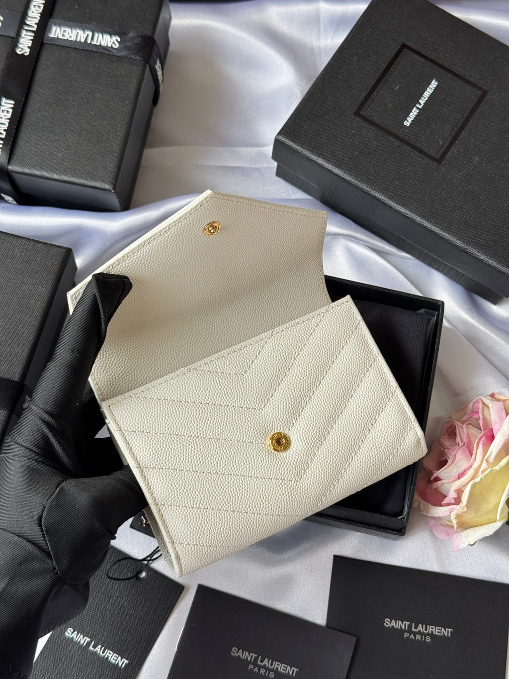 Small bag in light cream with gold Saint Laurent logo, shown from angled views