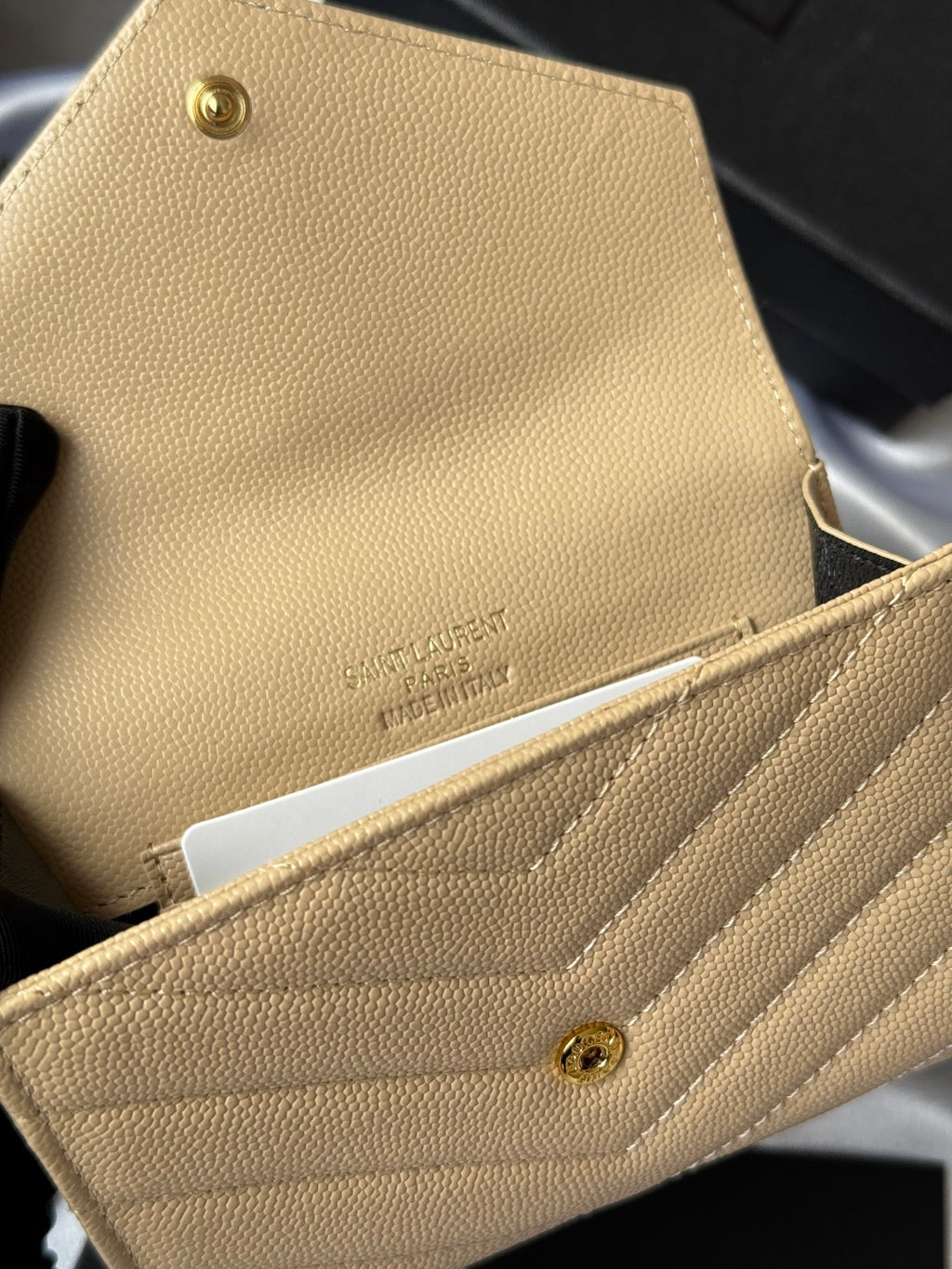 Small bag wallet close-up in light yellow textured leather with brand stamp and snap