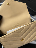 Small bag wallet close-up in light yellow textured leather with brand stamp and snap