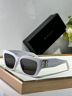 Balenciaga sunglasses with white frames, dark lenses, and gold B B emblem.