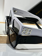 Balenciaga sunglasses side view with white frames, dark lenses, and gold B B logo.