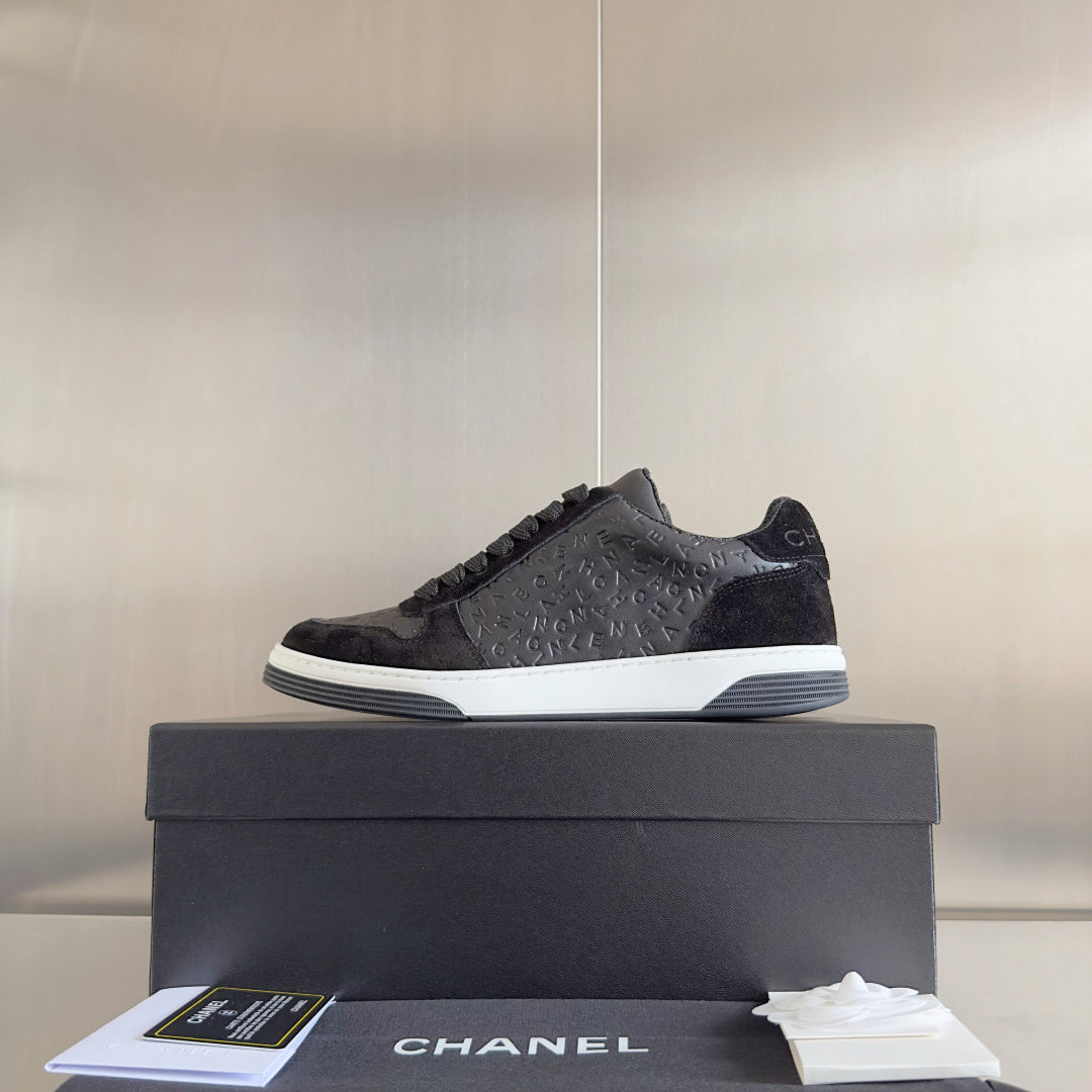 Black Chanel low-top sneakers on box, textured logo upper and white sole