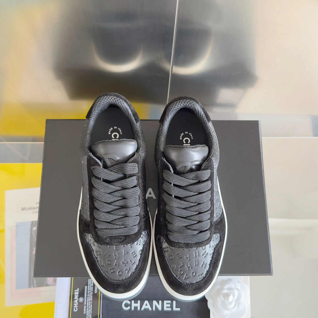 Black Chanel lace-up sneakers front view, textured logo upper and white midsoles