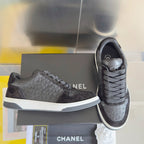 Black Chanel low-top lace sneakers with textured logo pattern and white sole