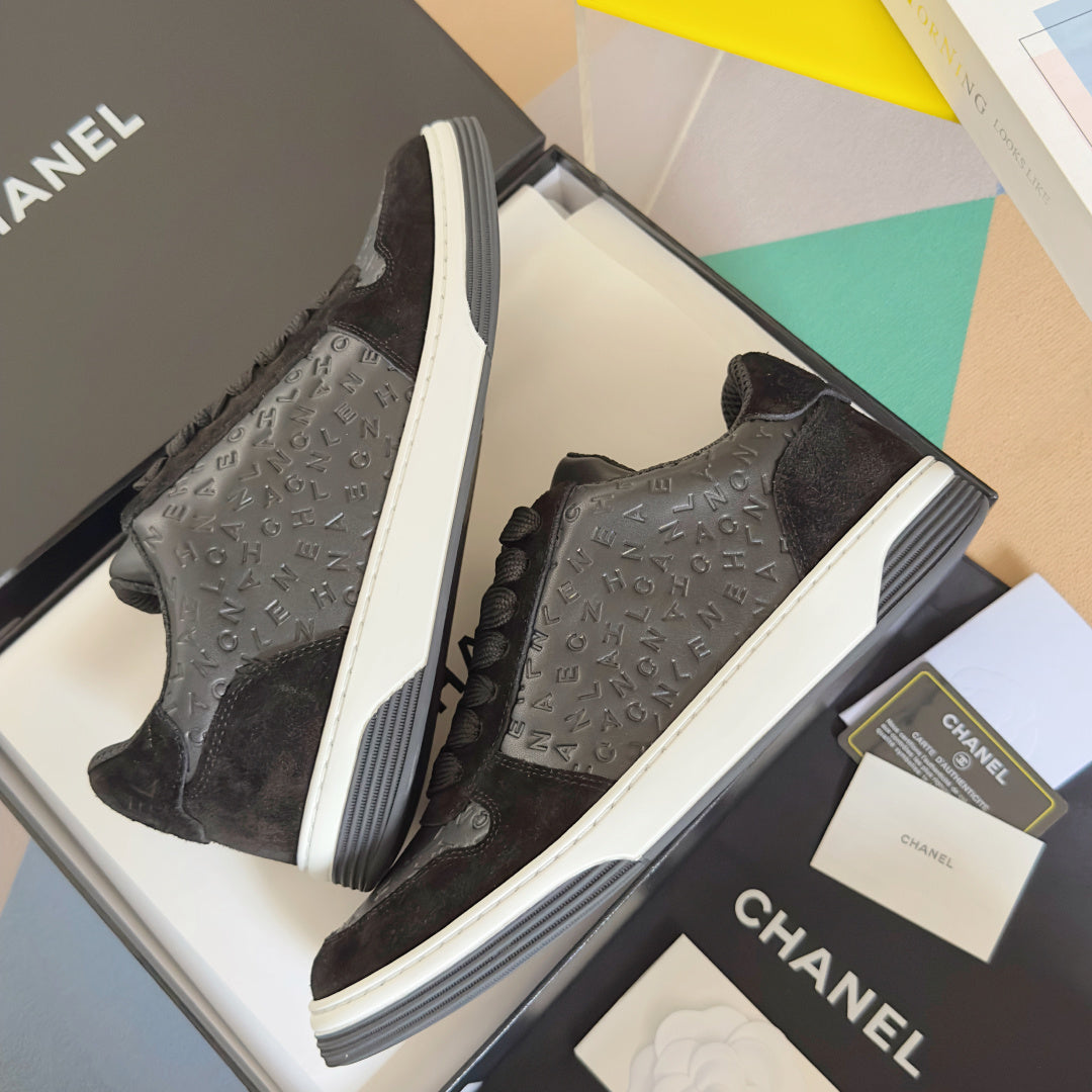 Black Chanel lace sneakers angled pair, white soles, textured logo panels