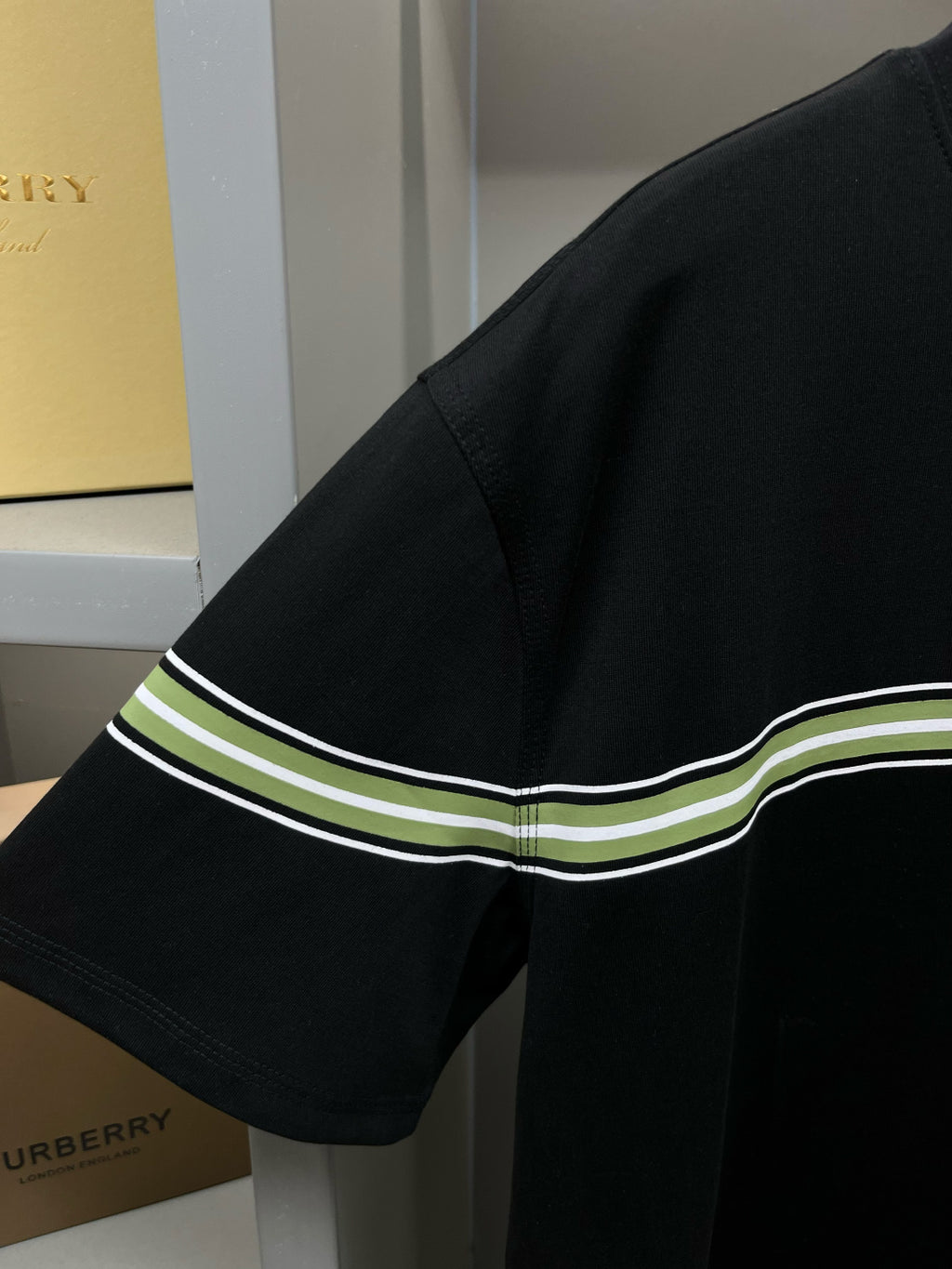 Black short-sleeve T-shirt sleeve with green-and-white stripe trim at hem