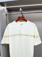 White Burberry T-shirt with gold stripe band across chest, on hanger