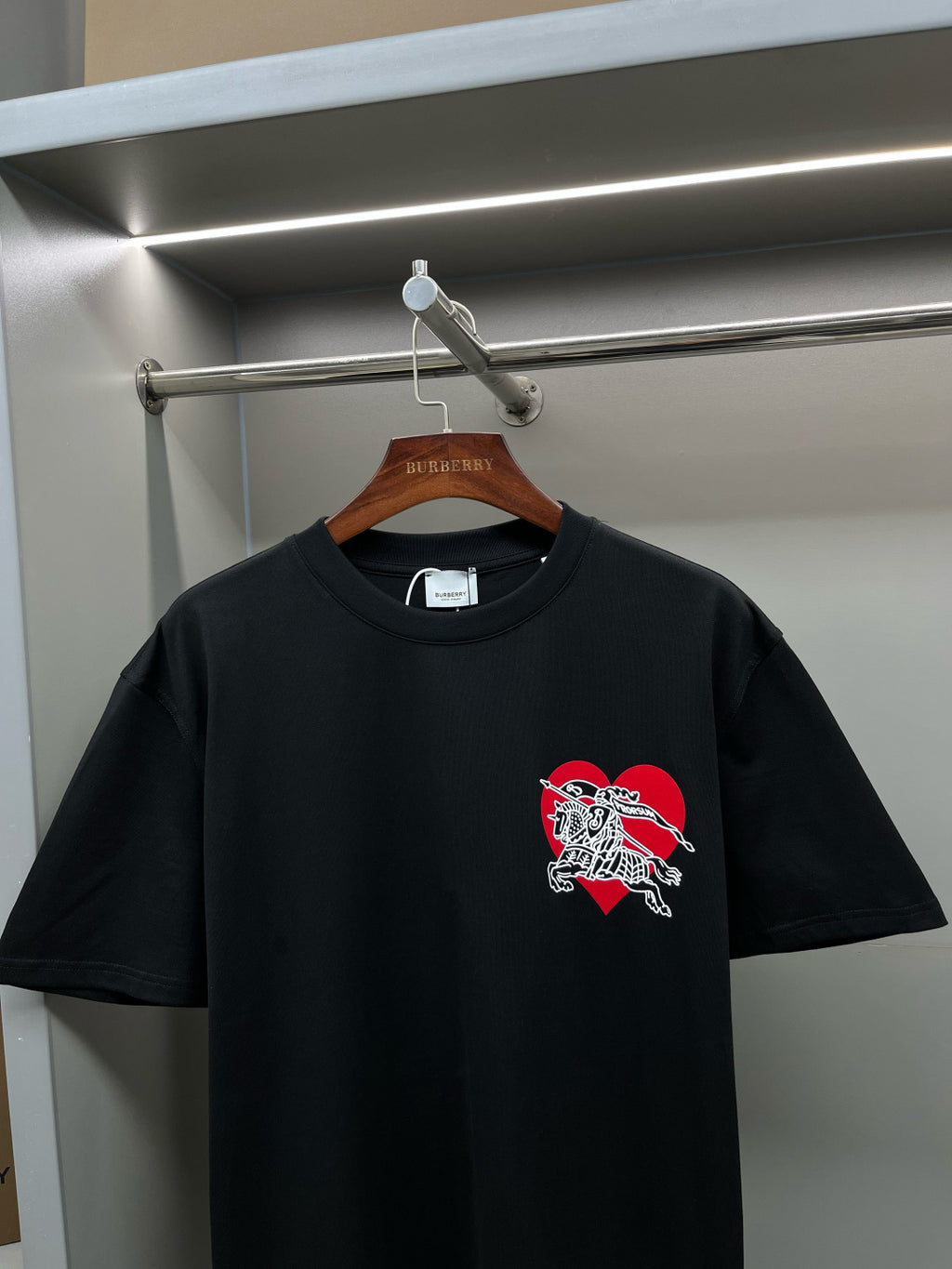 Black short-sleeve T-shirt with red and white horse emblem at center chest