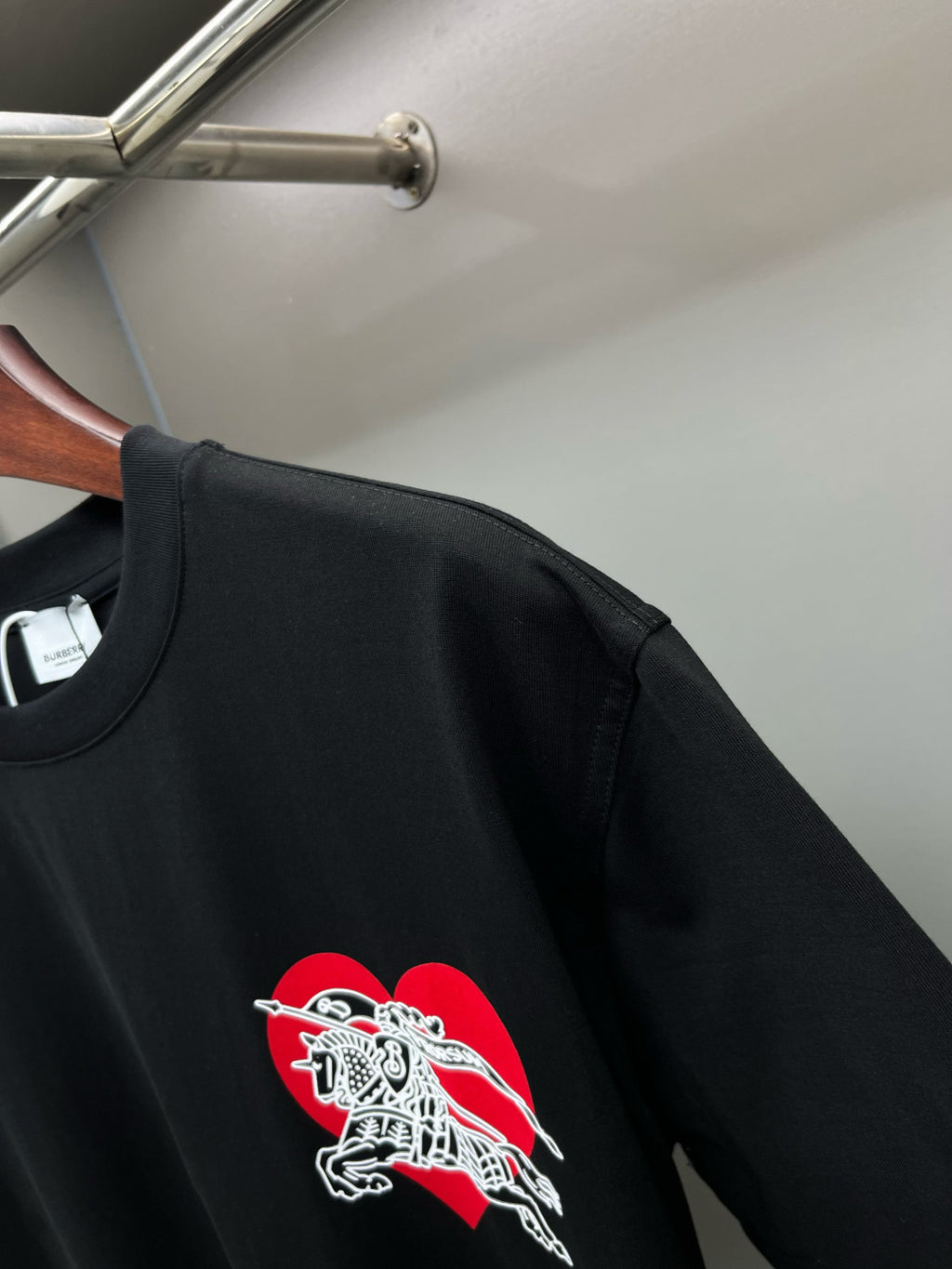 Black short-sleeve T-shirt with red and white horse logo near left chest
