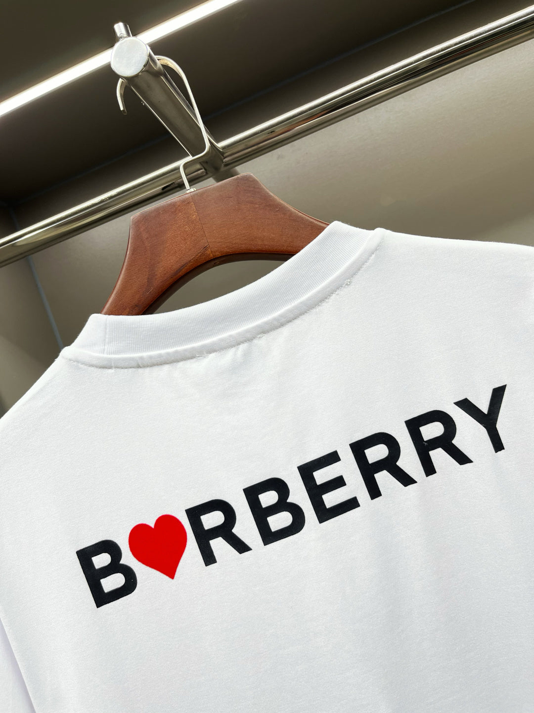 Close-up of white T-shirt back with black BURBERRY text and red heart B