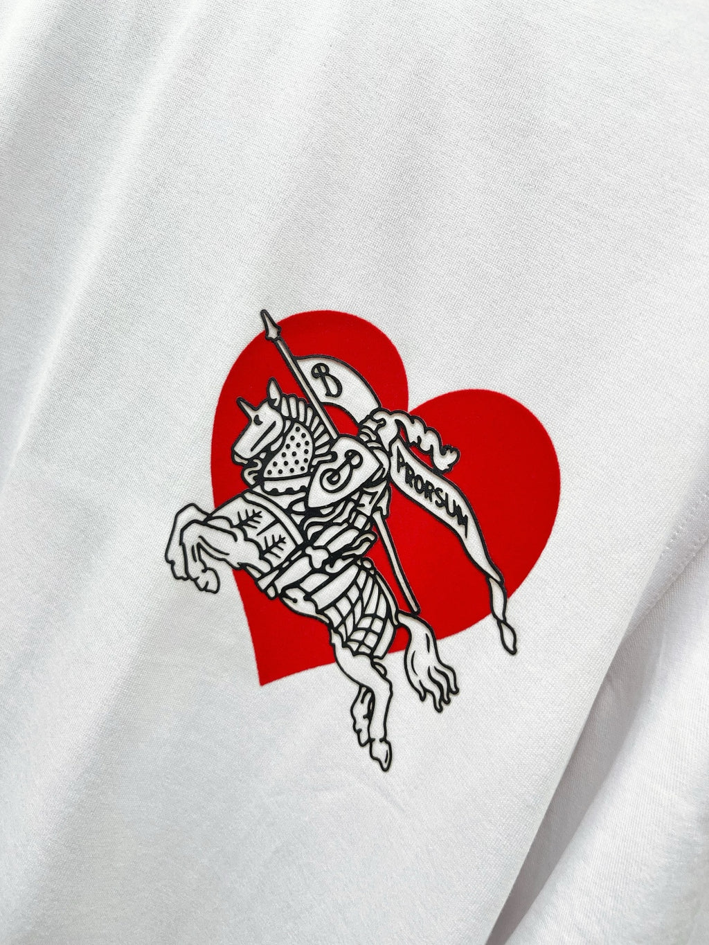 Close-up of white T-shirt with red heart and knight graphic