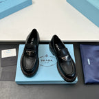 Black Prada unisex loafers, angled view with triangular logo straps