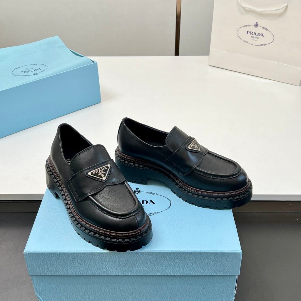 Black Prada unisex loafers on box, side angle showing strap logo