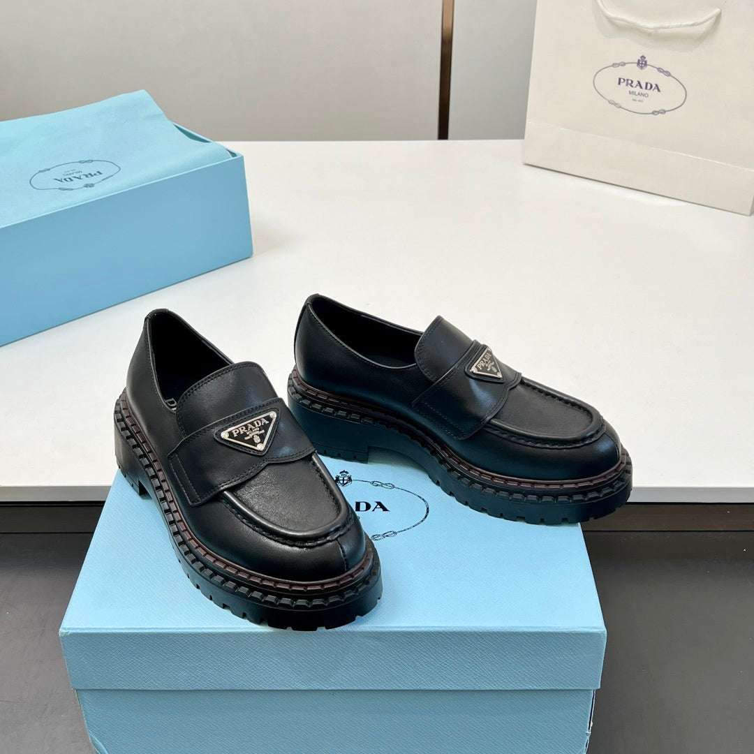 Black Prada unisex loafers on box, side angle showing strap logo