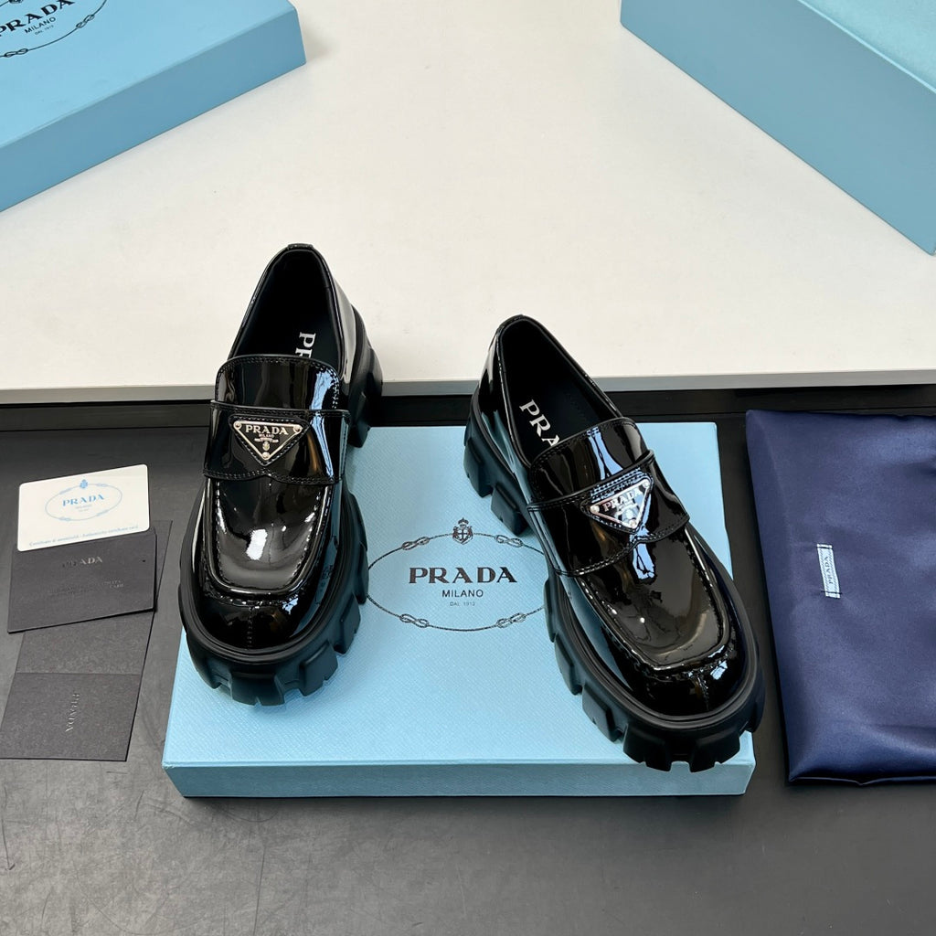 Black patent leather loafers with strap buckle and chunky platform lug sole