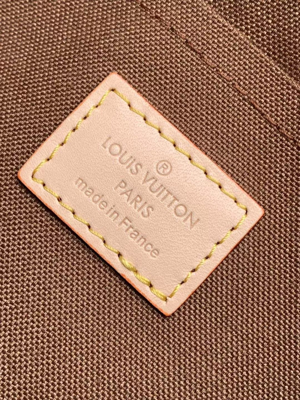 Louis Vuitton Paris leather label patch on brown fabric, stitched edges