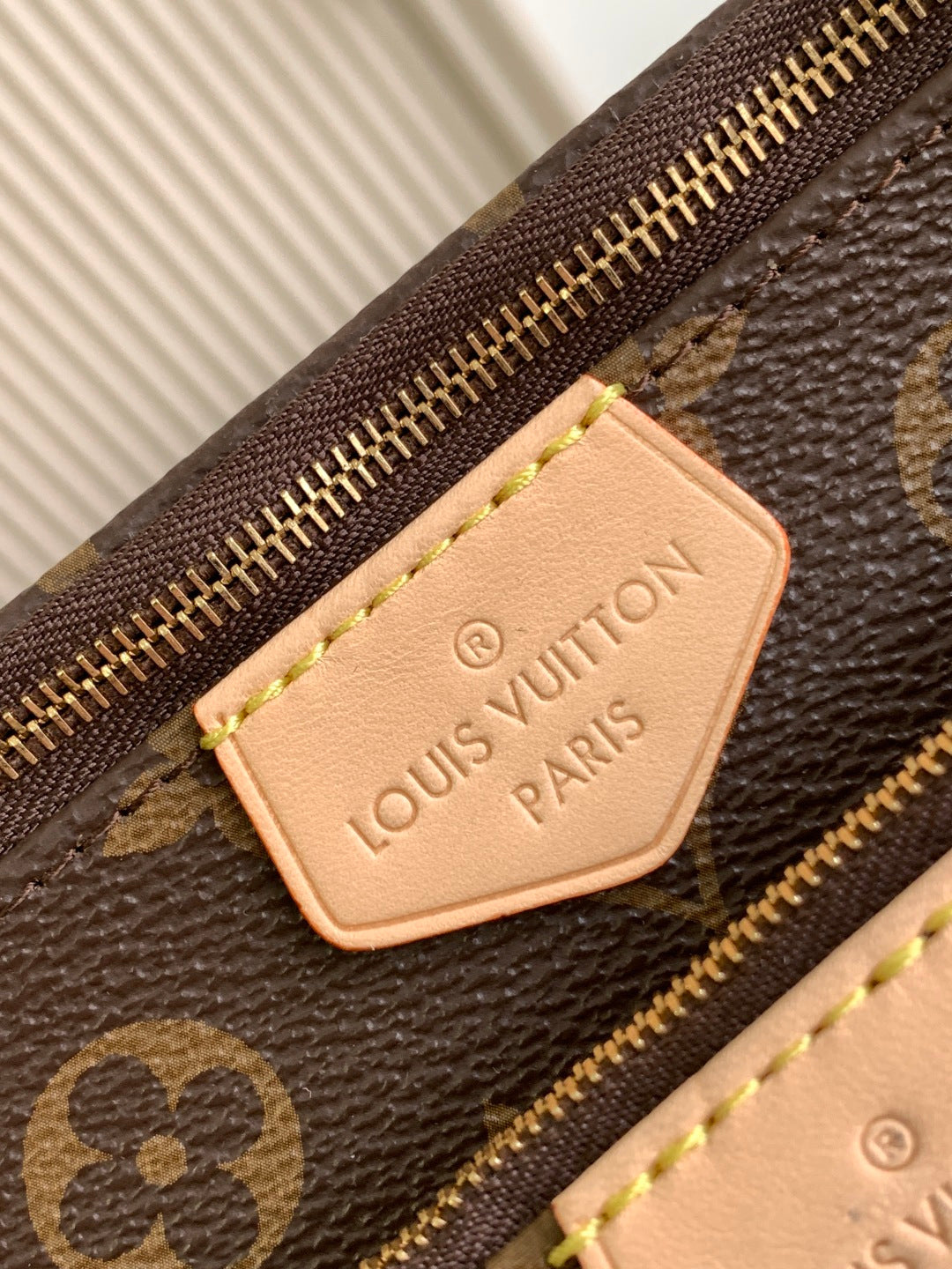 Louis Vuitton monogram bag with leather logo patch and gold zipper detail