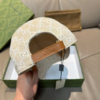 Gucci cap with beige GG monogram fabric and brown leather strap detail.