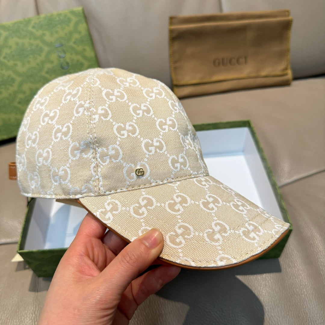 Gucci baseball cap with beige GG monogram fabric, brim view held in hand.