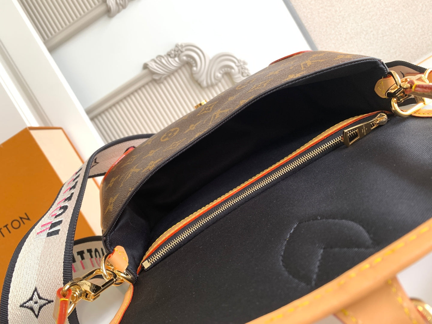 Monogram canvas bag opening with black lining and gold zipper pull