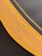 Embossed leather panel with text and yellow edge stitching on monogram canvas
