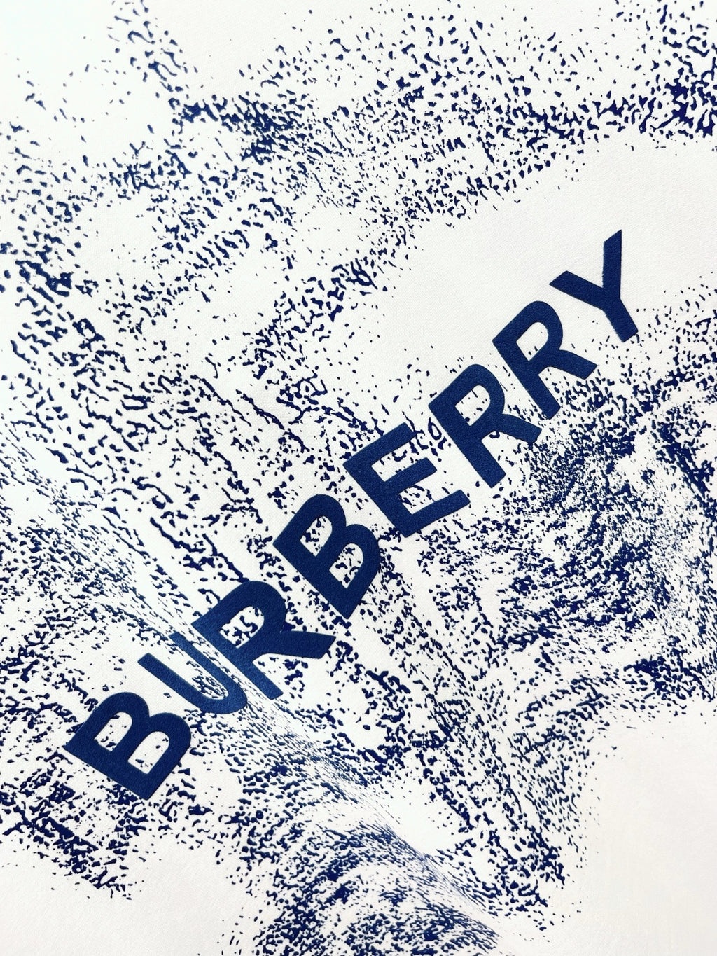 White T-shirt close-up of blue Burberry logo text splash print